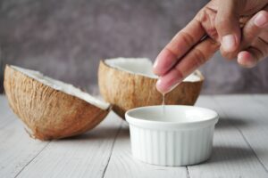 Unrefined coconut oil being scooped from a fresh coconut into a small bowl