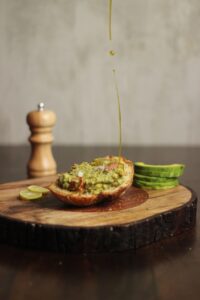 Oil being drizzled over avocado toast, representing healthy seed oil alternatives like avocado and olive oil